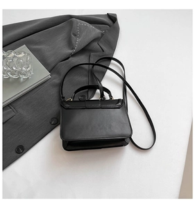 Detail of minimalist black rectangle crossbody bag with top handle on professional flat lay