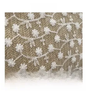 Détail du tissu du sac en paille avec broderie de marguerites blanches sur tulle fin