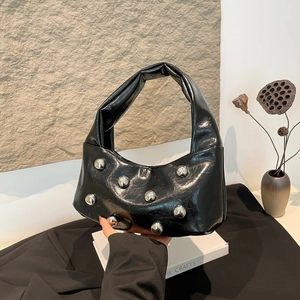 Chic black patent leather hobo bag with large silver studs and crescent shape design