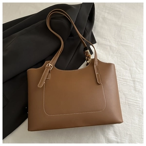 Detail of vintage brown leather tote bag with white stitching and decorative silk scarf