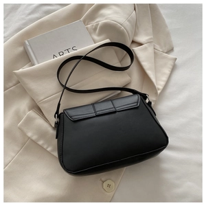 Flat lay of a black minimalist crossbody bag on a beige blazer with a sleek matte finish