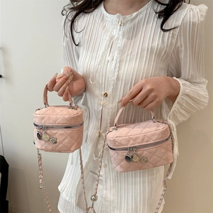 Pink quilted chain mini crossbody bag with camellia charm decoration shown in hand