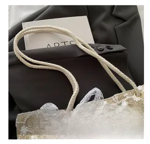 Détail du sac cabas tissé beige avec broderies florales blanches et anse en corde