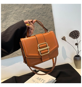 Detail of orange brown faux leather crossbody bag with elegant gold metal clasp and top handle