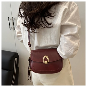 Model wearing a burgundy leather saddle bag with gold metal buckle and striped silk scarf