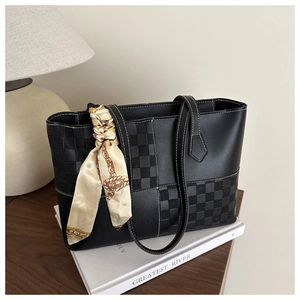Detail of black faux leather tote with checkered texture and silk scarf accessory