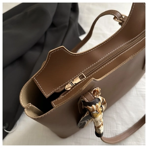 Detail of vintage brown tote bag with metal zipper and decorative printed silk scarf