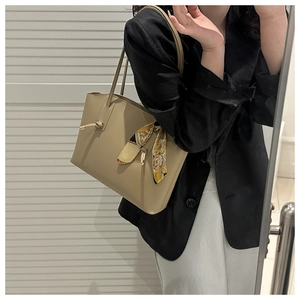 Detail of a chic beige tote bag with a floral silk scarf wrapped around the handle