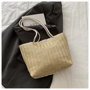 Minimalist beige woven tote bag with rope handles on white fabric and blazer background
