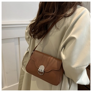 Brown leather underarm bag with silver round twist lock shown on a trench coat model