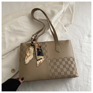 Close-up of khaki shoulder bag with checkered texture and decorative silk scarf detail