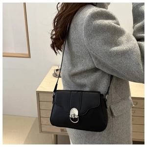 Detail of a black matte leather crossbody bag featuring a silver ring metal clasp buckle