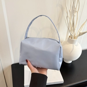 Close-up of light blue minimalist handbag with soft gloss finish and silver zipper detail