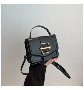 Detail of black structured handbag with polished gold buckle and premium faux leather texture