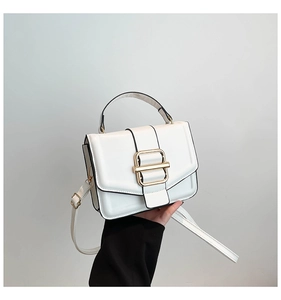 Detail of white textured structured handbag with elegant gold rectangular metal buckle lock