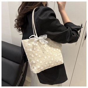 Detail of floral embroidery and lace bow on ivory woven straw shoulder tote bag