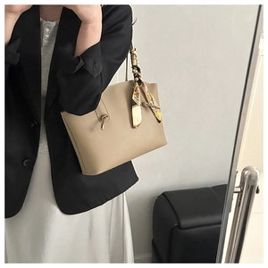 Detail of light khaki tote bag with elegant floral scarf wrapped around the handle