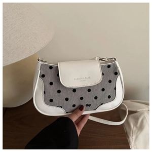 Détail du sac bandoulière à pois avec bordure en cuir et logo nœud doré élégant