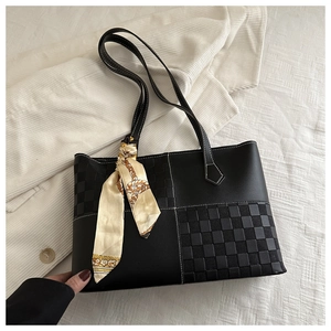 Detail of black plaid tote bag featuring white stitching and decorative silk scarf wrap