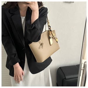 Large khaki tote bag featuring knotted handles and an elegant printed silk scarf detail