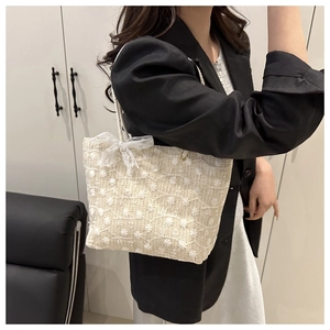Detailed shot of beige woven tote bag with lace flowers and mesh bow on model