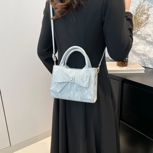 Sac à main plissé bleu clair avec grand nœud et boucle coeur porté par un mannequin