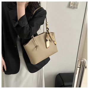 Detail of khaki tote bag with vintage silk scarf on handle, shown in a chic outfit style