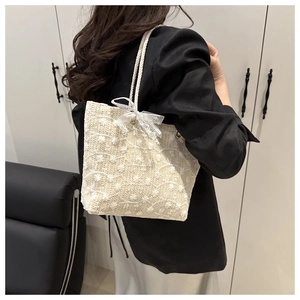 Detail of a beige woven tote bag with 3D flower embroidery and lace bow accent