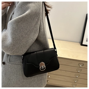 Detail of minimalist black leather crossbody bag with silver ring clasp on a model