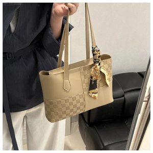 Detail of beige faux leather tote with checkered texture and decorative handle scarf