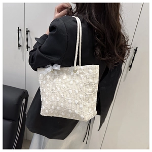 Détail du sac fourre-tout tissé crème avec broderie florale et nœud en dentelle blanche