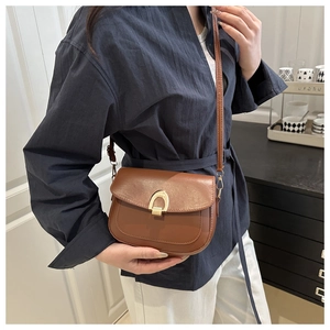 Detail of caramel brown saddle bag with matte gold metal buckle and leather strap