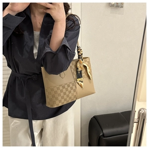 Detail of checkered tote bag with scarf-wrapped handle and beige leather contrast