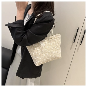 Close-up of white woven tote bag with floral embroidery and delicate lace trim detail