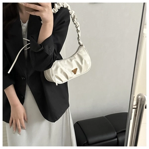 Detail der weißen Hobo-Tasche mit dreieckigem Metalllogo und gerafftem Schulterriemen im Trend