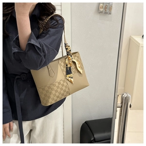 Detail of khaki tote bag with checkerboard panel and decorative silk scarf on handle