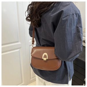 Model wearing a retro dark brown saddle bag with golden U-shaped buckle decoration
