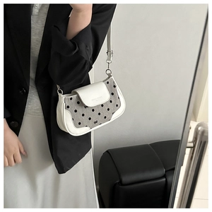 Gros plan détaillé d'un sac à main en cuir blanc avec tissu à pois gris et boucle argentée