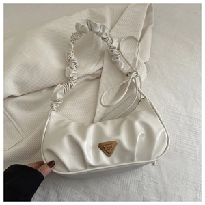 Detail view of white ruched handbag with metal triangle logo on white corduroy background