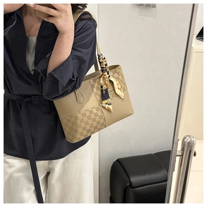 Dettaglio borsa tote in pelle kaki con trama a scacchi e sciarpa di seta decorativa