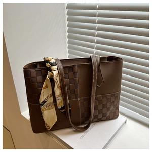 Detail of a brown plaid tote bag with silk scarf on handle and textured leather finish