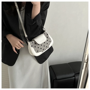 Détail d'un sac à bandoulière vintage à pois avec garniture en cuir blanc sur modèle