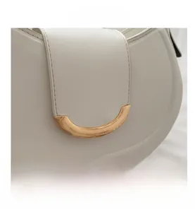 Close-up of white leather hobo bag featuring a brushed gold crescent moon metal buckle