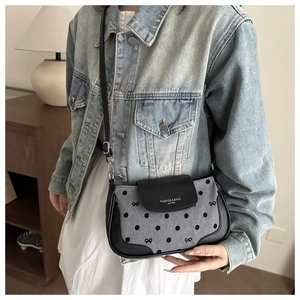 Détail d'un sac bandoulière demi-lune avec pois et finitions en cuir noir