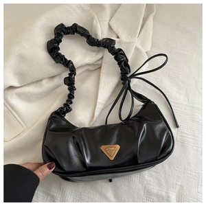 Close-up of black ruched leather handbag featuring metal logo and bow detail