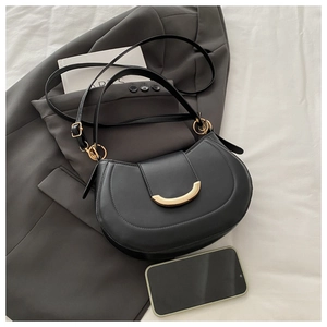 Detail of black leather half-moon bag with gold crescent buckle on a blazer background