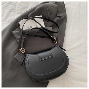 Detail of matte black saddle bag with gold metal ring buckle on grey suit jacket