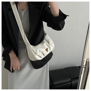 Detail shot of a white pleated crossbody bag featuring a glossy finish and golden triangle logo