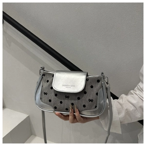Detail of grey polka dot crossbody bag with silver trim and metallic logo texture