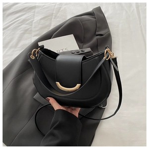 Detail of minimalist black crescent bag with elegant gold metal buckle and leather strap